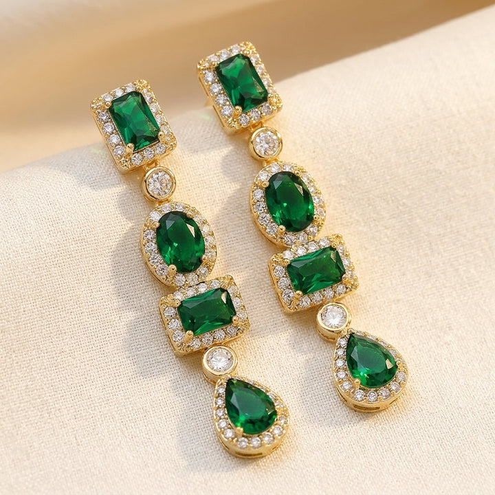 Brincos de ouro com esmeraldas em múltiplas formas, estilo gota, da marca Rose & Oliver, detalhes elegantes e sofisticados.