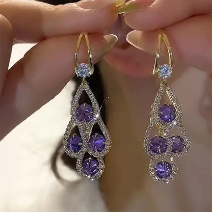 Aretes de gota con cristal morado de Rose & Oliver, elegantes y brillantes, colgados en alambre de metal plateado.