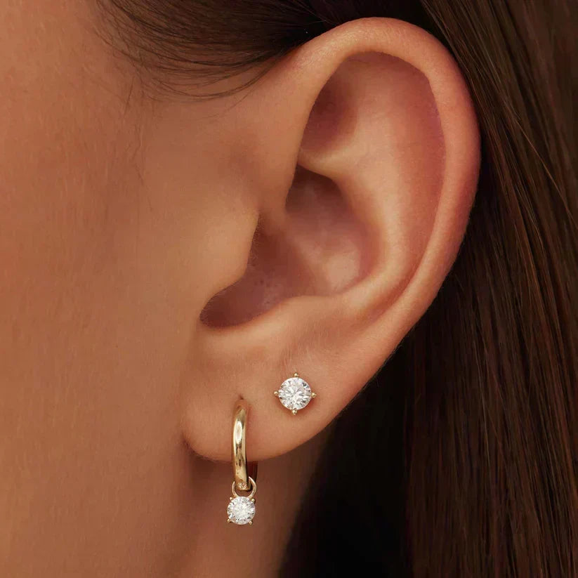 Aretes de metal dorado Larmes™ con piedra, estilo clásico, de la marca Rose & Oliver, en primer plano en la imagen.